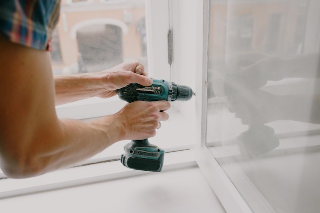 person drilling window into place